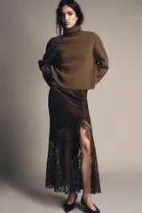 Falda midi de tiro alto confeccionada en tejido satinado color marrón. Presenta un diseño evasé con aplicación de encaje en el lateral y el bajo, y cierre lateral con cremallera oculta.