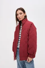 Campera bomber de gabardina con diseño capitoneado, cuello alto, cierre frontal con botones a presión ocultos y mangas abullonadas con puños elásticos.