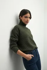 Polera de cuello alto con textura tramada, manga larga con puños acanalados y diseño holgado.