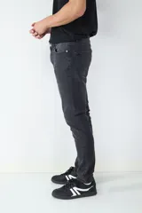 Jean de corte slim fit en color negro lavado, con diseño clásico de cinco bolsillos, cierre frontal con botón y cremallera.