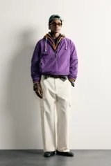 Pantalón cargo relaxed fit de color blanco, confeccionado en tejido de algodón. Presenta bolsillos de plastrón con solapa en las perneras y cierre frontal con cremallera y botón.