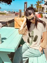 Sweater de punto color beige con mangas ranglan color marrón y aplique de cuero con forma de cactus en el frente.