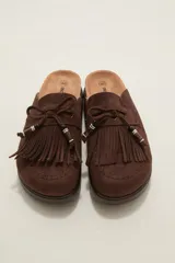 Suecos tipo mocasín color chocolate, confeccionados en material gamuzado. Presentan un diseño con flecos frontales, cordones decorativos con cuentas y una suela de plataforma plana de goma.