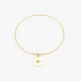 Esclava de alambre redondo en oro 9k con medalla colgante circular que presenta un diseño de estrella grabada con una circonia central.