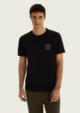 Remera negra de corte regular con cuello redondo, manga corta y pequeño estampado circular en el pecho.
