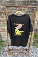 Remera negra con estampa de bananas amarillas y lilas, con texto en tipografía vintage.