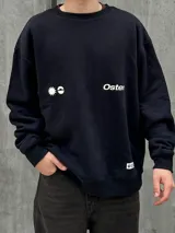 Buzo negro de corte holgado con cuello redondo y puños y bajo acanalados. Estampado frontal con un sol y la palabra "Osten" en blanco.
