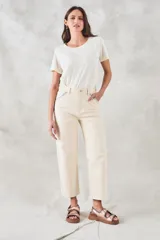 Pantalón jean color crudo, de tiro medio y corte recto, con bolsillos delanteros con bordado de motivos geométricos en tonos celeste y naranja.