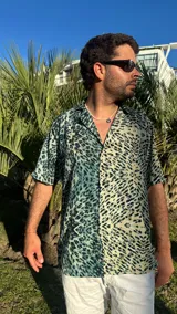 Camisa de manga corta con estampado abstracto en tonos verde, beige y negro.