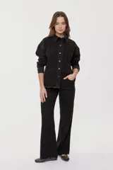 Sobrecamisa de denim negro con calce relajado, mangas largas, cuello clásico, cierre frontal con botones y bolsillo aplicado. Cuenta con detalles de strass en toda la prenda y terminación desflecada en el bajo.