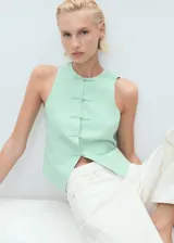 Chaleco verde menta sin mangas, con cuello redondo y cierre frontal con nudos y presillas de tela.