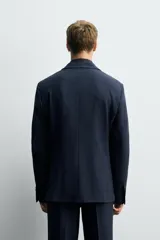 Blazer de corte slim fit confeccionada en tejido con viscosa, con cuello de solapas de muesca, manga larga con puños abotonados, bolsillo de vivo en el pecho, bolsillos con solapa en la cadera y cierre frontal con botones.