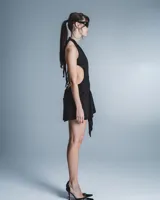 Minivestido negro con escote halter pronunciado, espalda descubierta, falda drapeada y lazo decorativo en el frente.