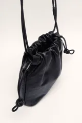 Bandolera negra de cuero ovino con fruncido superior y correa ajustable.