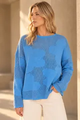 Buzo de tejido de punto calado color celeste, con diseño de flores, escote redondo y mangas largas.