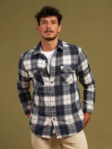 Camisa a cuadros azul marino y beige, de manga larga, con cuello clásico y dos bolsillos con solapa abotonada en el pecho.