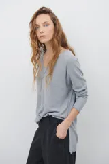 Sweater de tejido de punto color beige, con escote en V y mangas largas. Presenta un diseño básico y versátil de corte recto.