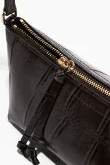 Cartera tipo baguette de color marrón oscuro con acabado brillante y textura efecto cocodrilo. Cuenta con un cierre superior, correa de hombro ajustable y detalles metálicos.