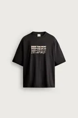 Remera negra de corte relaxed fit, con cuello redondo, manga corta y bordados a contraste en el delantero con la frase "Drop the beat".