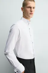 Camisa slim fit de algodón con cuello smoking, manga larga con puño doble para gemelos y pechera combinada a tono con cierre frontal de botones.