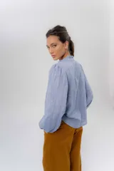 Camisa de manga larga color beige con diseño a rayas sutiles, cuello mao con volados y abertura frontal con detalles de volados a un lado.