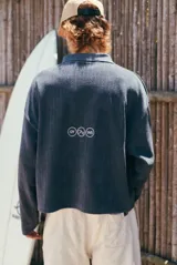 Buzo gris de tejido de punto con textura acanalada, cuello polo y escote en V. Presenta un estampado frontal con la inscripción 'glassy wa'.