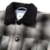 Campera a cuadros gris y negra con cuello de pana negro, cierre con botones, bolsillos de parche en el pecho y corte recto.