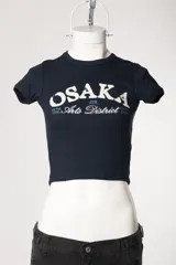 Remera baby tee de morley color chocolate, de calce ajustado al cuerpo y manga corta, con cuello redondo y diseño estampado frontal.