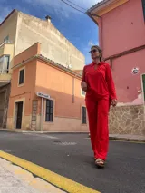 Pantalón rojo de corte recto y tiro alto, con bordado tipo broderie en la parte inferior de las piernas.