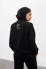 Canguro negro de algodón con frisa PIMA, corte oversized y etiqueta con logo en la manga.