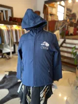 Campera de neopreno azul marino con capucha, cierre frontal completo y bolsillos laterales con cierre. Presenta un bordado en el pecho con la silueta de un caballo y la inscripción "Criollos".