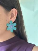 Aro de gran tamaño en forma de flor color turquesa, con diseño central de estrella en glitter violeta.