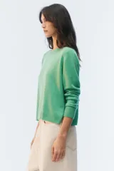 Sweater de tejido de punto verde, con calce regular levemente suelto, escote redondo y mangas largas con puños acanalados.