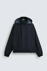 Cazadora de ajuste regular, color azul marino oscuro, confeccionada en tejido técnico repelente al agua. Presenta cuello subido con capucha desplegable, manga larga con puño elástico, forro interior de red, bolsillos de vivo en cadera y bajo con elástico. Cierre frontal con cremallera oculta por solapa de botones a presión.
