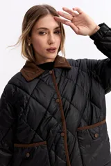 Campera matelaseada de diseño en rombos, color negro con cuello y detalles de ribete en color marrón. Cuenta con cierre frontal de botones a presión y bolsillos delanteros con solapa.