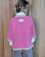 Buzo de lana lambswool en color lila, con cuello redondo, puños y ruedo en tono beige contrastante. Presenta un diseño holgado de manga corta con terminación acanalada.