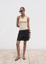 Top de punto fino color beige, con cuello barco y tirantes finos, de diseño entallado y sin mangas.
