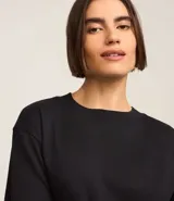 Blusa de manga corta confeccionada en algodón pima, con cuello redondo y diseño liso. Presenta un corte clásico con el bajo ligeramente más largo en la parte posterior.