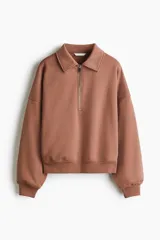 Buzo de algodón con interior cepillado, cuello camisero, medio cierre frontal y hombros caídos. Presenta puños y bajo acanalados.