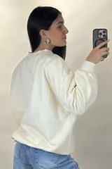 Buzo de cuello redondo, corte oversize, con mangas largas y puños elásticos.