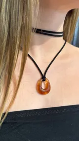 Conjunto de gargantilla tipo choker de doble vuelta y collar largo con cordón negro y dije de resina en forma de gota color ámbar.