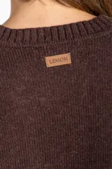 Sweater de tejido de punto liso, color marrón oscuro, con cuello redondo y calce oversize. Presenta detalles de costura en diagonal en la parte inferior delantera.