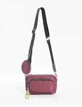 Bandolera de nylon color vino tinto, con correa ajustable estampada en negro y herrajes metálicos. Incluye un monedero pequeño desmontable y un llavero de cordón trenzado color verde lima.