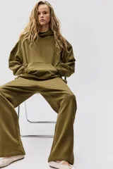 Buzo canguro color verde militar con capucha de doble capa, hombros caídos, bolsillo canguro y puños y bajo acanalados.