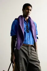 Camisa de corte relajado confeccionada en tejido de algodón de color azul, con cuello abotonado, manga larga, bolsillo frontal de parche y cierre de botones.