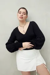 Top negro de tejido sutilmente metalizado, con escote en V y mangas abullonadas.