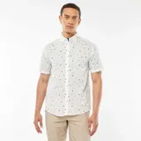 Camisa blanca de corte recto y manga corta, con estampado de palmeras, estrellas y lunas en color negro.