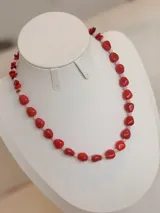 Collar de diseño artesanal compuesto por cuentas de coral en tono rojo e intercaladas con pequeños cristales facetados en color rosado claro.
