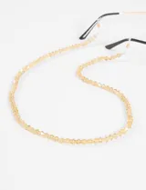 Correa para lentes compuesta por pequeñas cuentas de cristal facetado en tono dorado traslúcido, con terminales de silicona para sujeción.