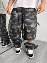 Pantalón baggy desmontable de gabardina con estampado camuflado en tonos grises y negros, de corte holgado y diseño convertible en short.